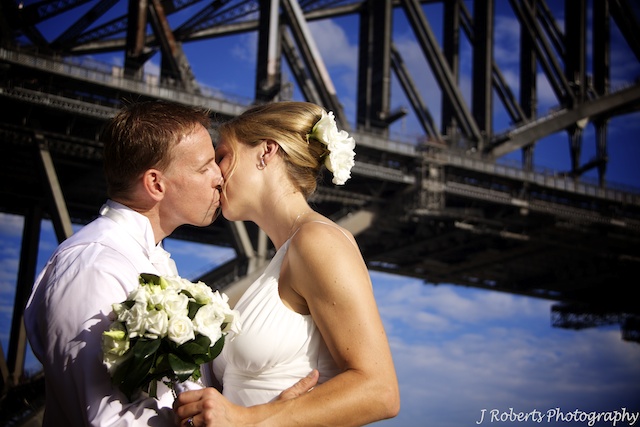 Bride and groom kissing in front of Sydney Harbour Bridge - wedding photography